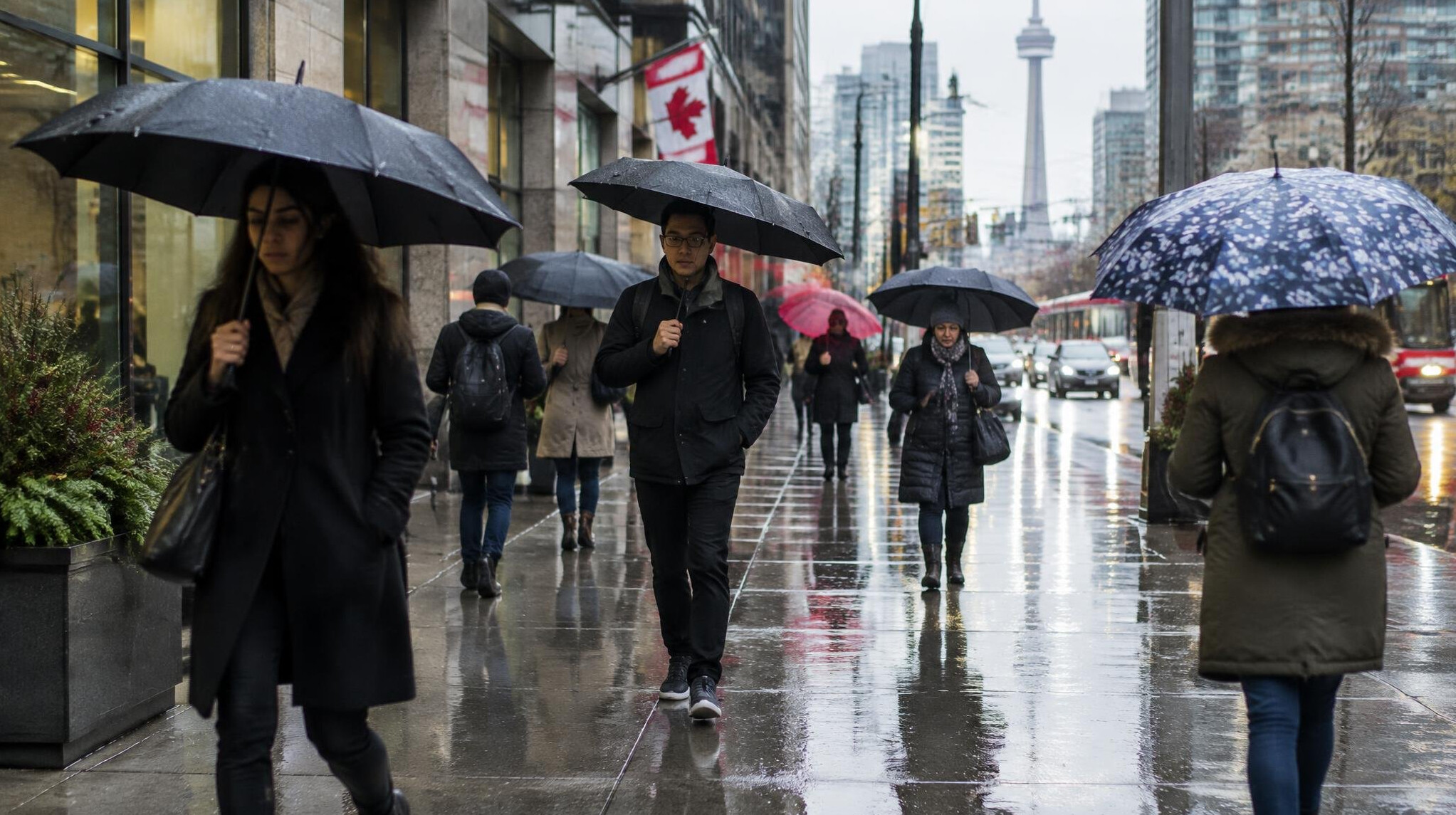 People walking on a rainy city sidewalk with umbrellas